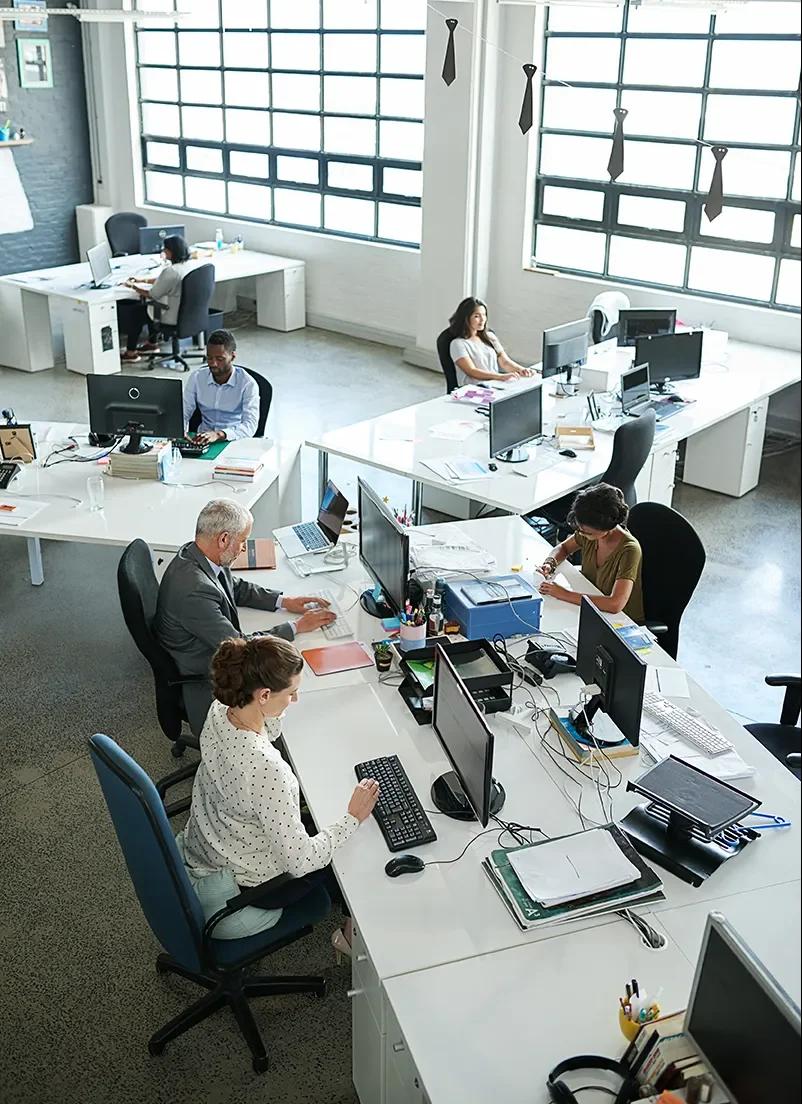 Busy open plan office of people sitting at desks using Dynamics 365 to perform their roles.