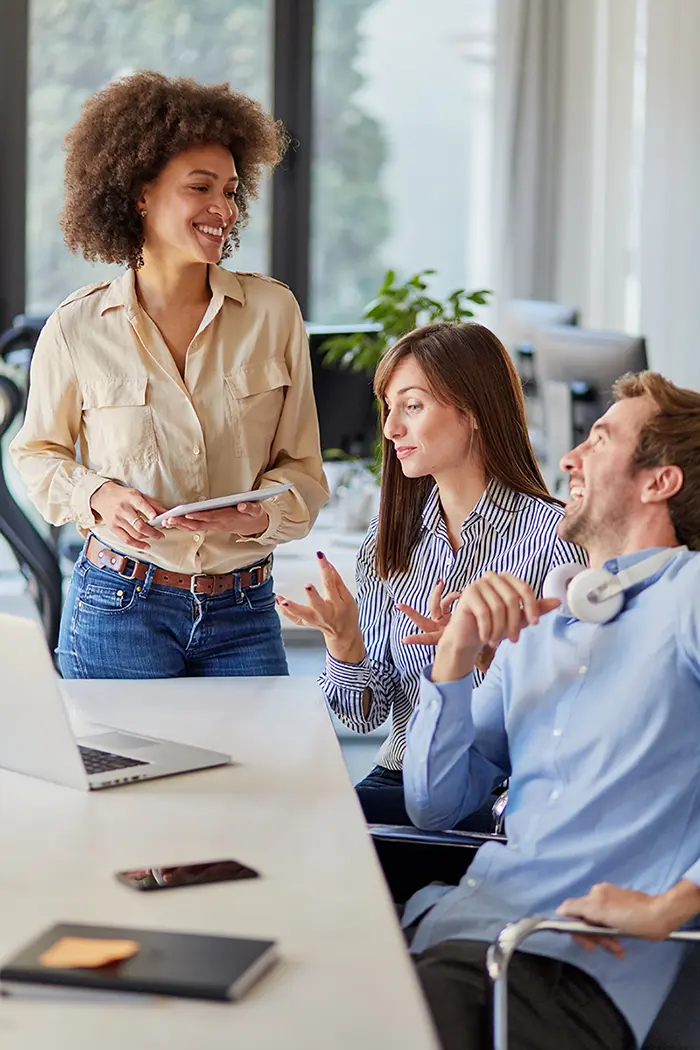 Group of three co-workers interacting in a meeting room.