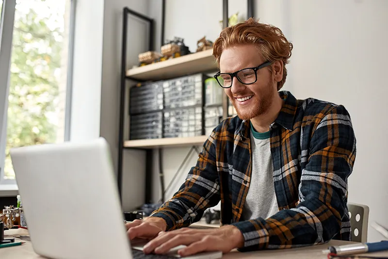 Millennial technician working on a laptop to provide Dynamics 365 partner services