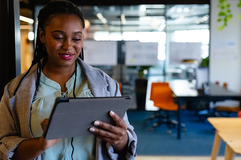 Female health services worker holding a tablet device to navigate a Dynamics 365 portal.