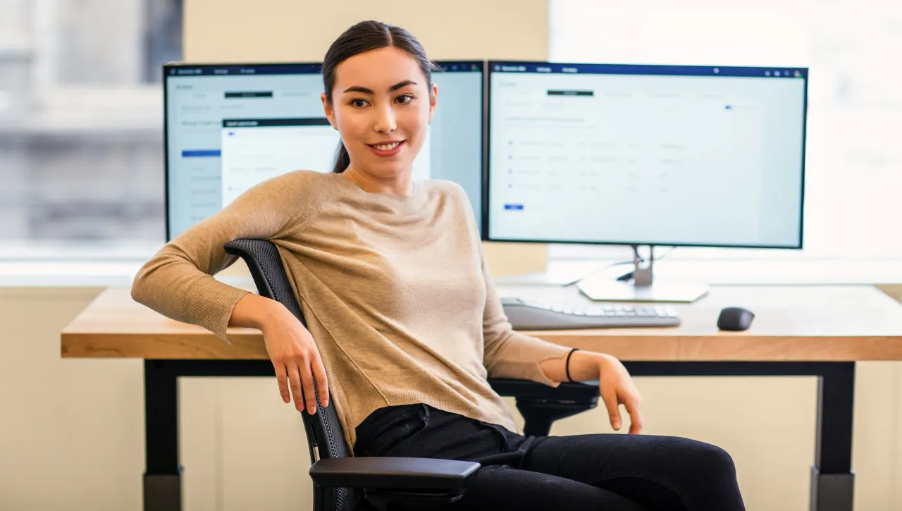 Female Power Platform user looking away from twin monitors