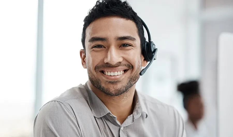 Young smiling support technician using Dynamics 365 to resolve a support ticket.